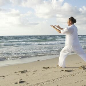 A serene scene of a man practicing Tai Chi on a quiet beach with gentle waves.